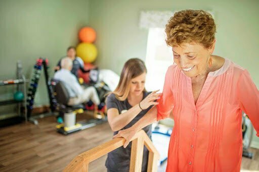Physical therapist helping an elderly woman with walking during her short-term rehabilitation stay