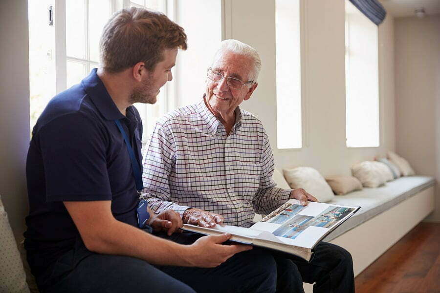 senior looking through a photo book with a male caregiver; Memory care for seniors