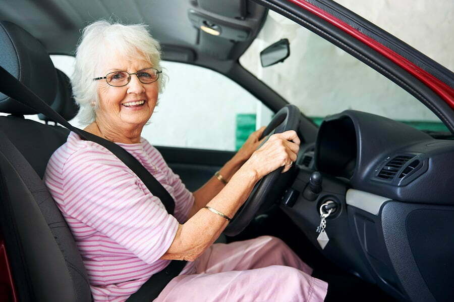 Smiling senior driving in a red car