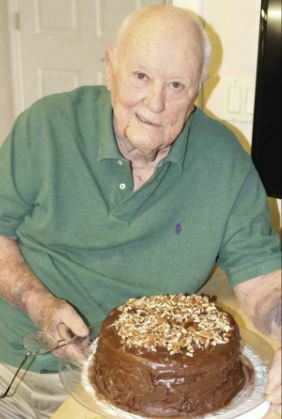 Fred Perkins, a resident at The Buckingham, posing with a cake he baked